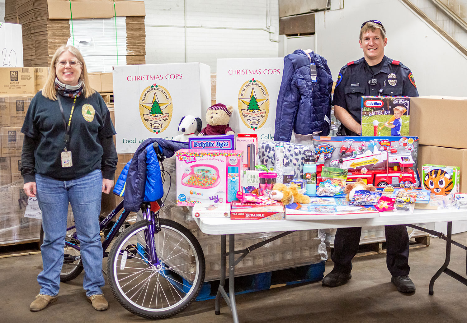 Heather Bowden, Public Information Coordinator for Plano Police, and Plano Police Officer Aaron Graham with the gifts and food boxes that will go to a family with two children