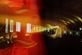 Guitarist lets chord ring out, with intentional motion blur. Cross-processed.