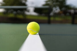Focus is on the tennis ball in the foreground with the background defocused